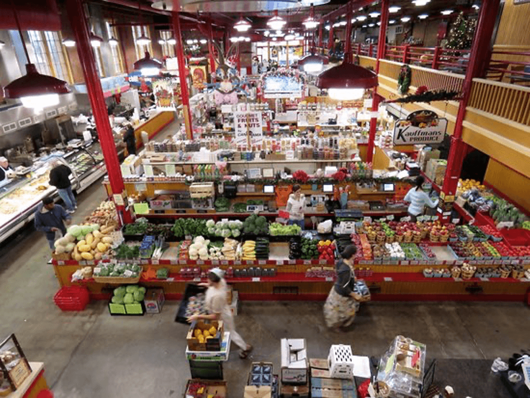 A busy market filled with colorful produce and shoppers navigating the aisles.