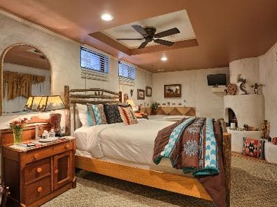 Cozy bedroom featuring a wooden bed, decorative pillows, a table lamp, and light-colored walls.