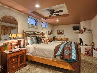 Cozy bedroom featuring a wooden bed, decorative pillows, a table lamp, and light-colored walls.