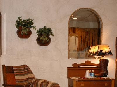 Cozy room corner featuring a rocking chair, decorative plants, a mirror, and a lamp on a side table.