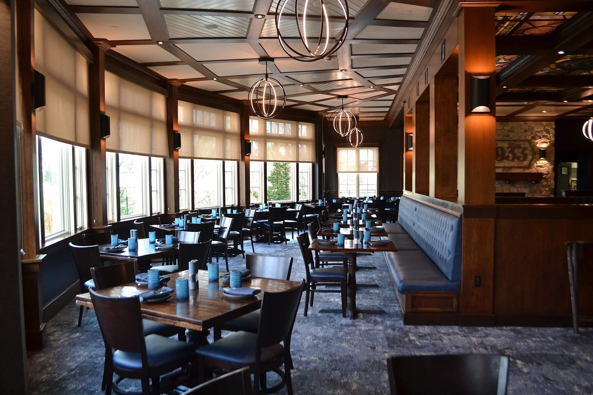 A spacious restaurant interior with wooden furniture and large windows.