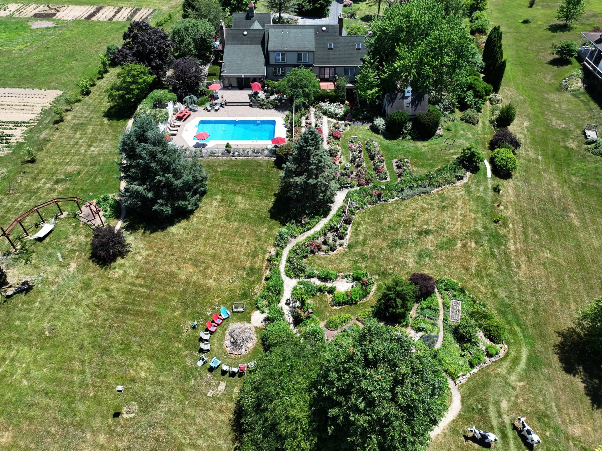 Aerial view of a spacious garden featuring a pool, flower beds, and seating areas.