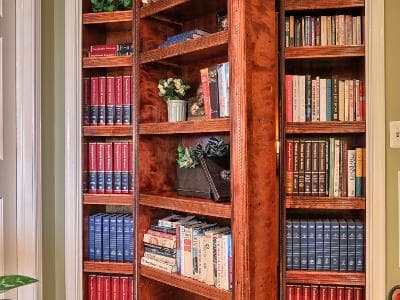 A wooden bookcase filled with various books and small green plants.