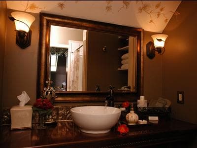 A stylish bathroom featuring a round wash basin, elegant lighting, and decorative elements.