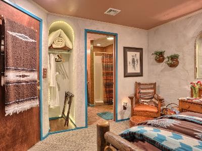 A cozy bedroom featuring rustic decor, a chair, and an entrance to a bathroom.
