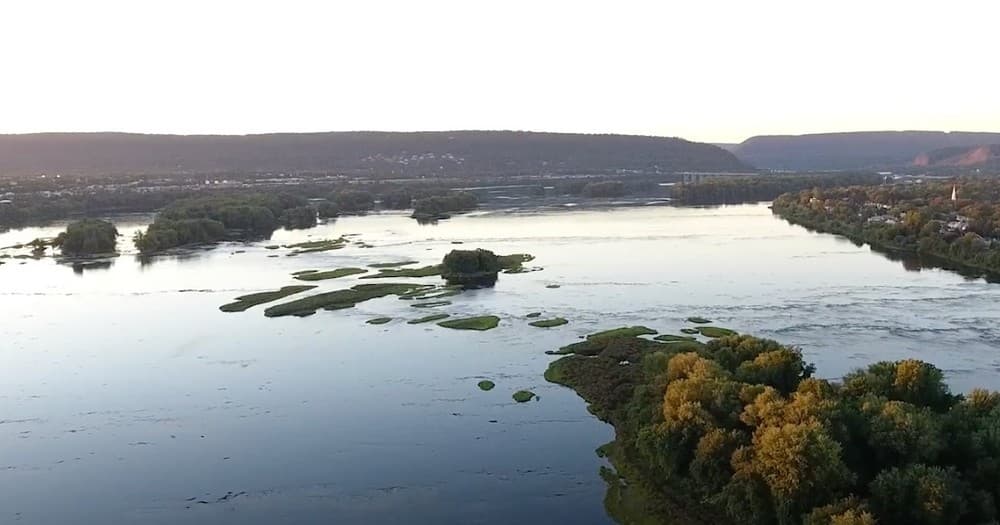 Aerial view of a serene river landscape with islands and lush greenery at sunset.
