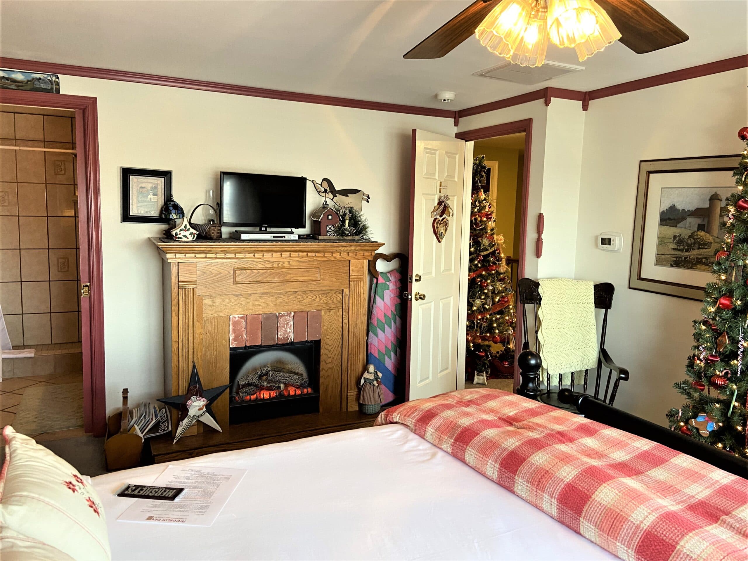 A cozy bedroom with a plush bed, fireplace, and festive Christmas decorations.