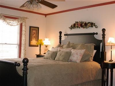Cozy bedroom featuring a queen-sized bed with decorative pillows, bedside lamps, and floral accents.