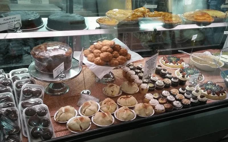 A display case filled with various cakes, cookies, and pastries.