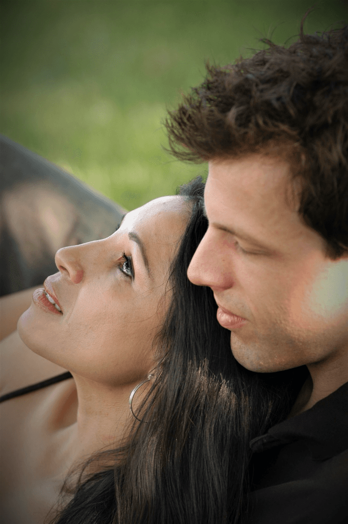 A couple gazes into each other's eyes, enjoying a moment together outdoors.