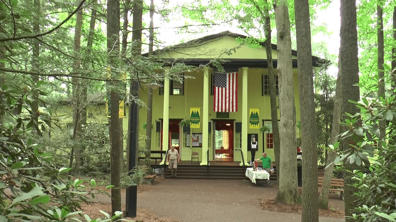 A vibrant yellow building with an American flag, surrounded by lush green trees.