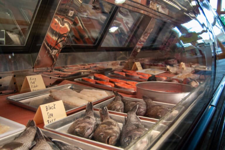 A display case filled with various types of fresh fish and seafood, labeled with names.
