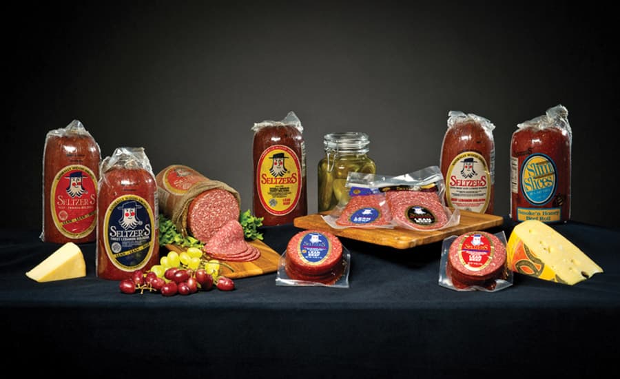An assortment of packaged meats, cheeses, and pickles displayed on a dark backdrop.
