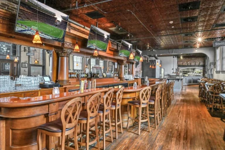 A stylish bar with wooden seating and multiple TVs displaying sports.
