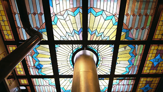 Colorful stained glass ceiling with geometric patterns and a central circular design.