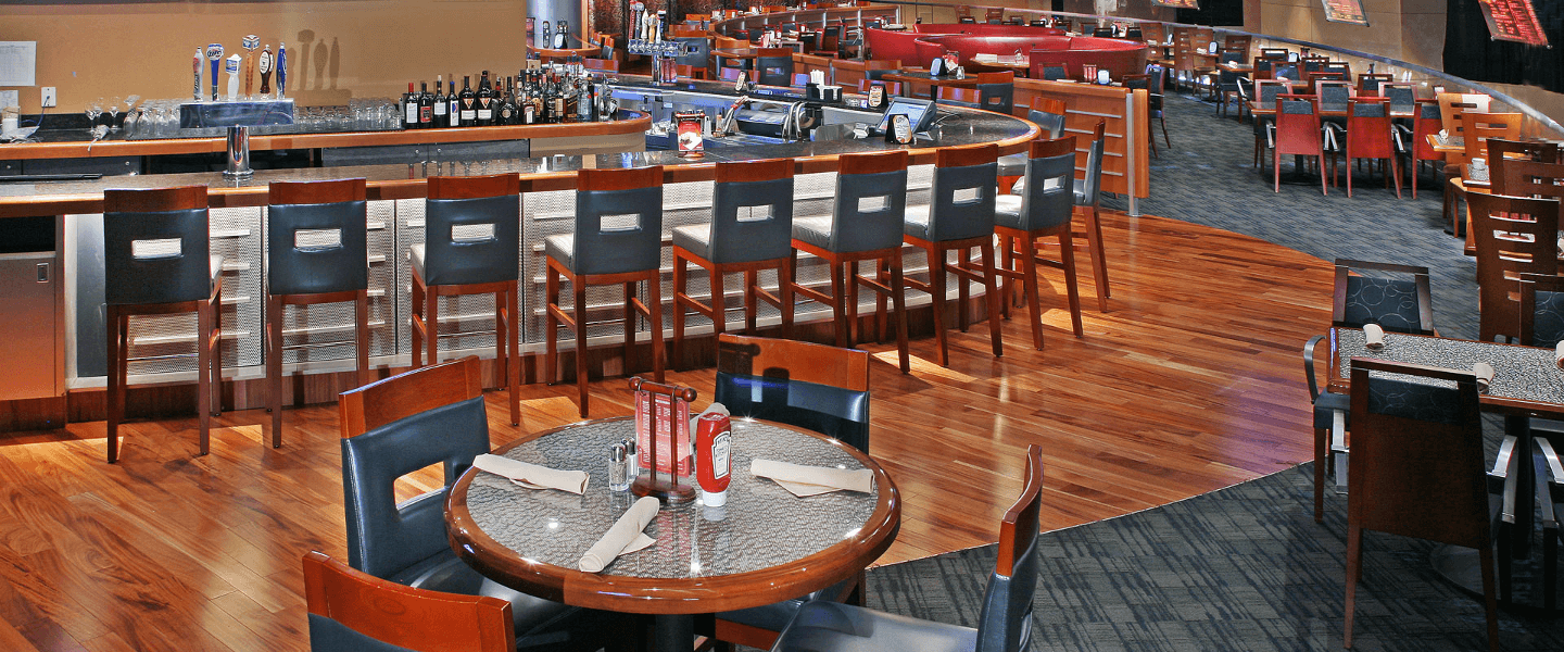 A spacious restaurant interior featuring a bar area and dining tables.