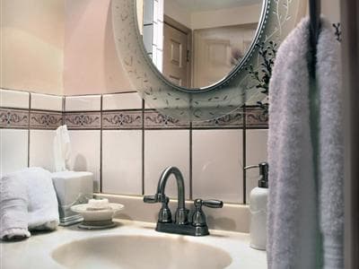 A neatly arranged bathroom sink area featuring towels, toiletries, and a round mirror.