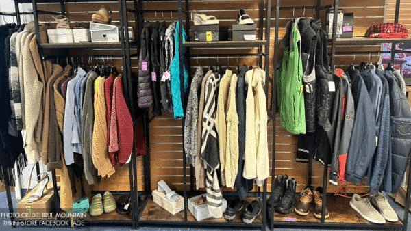 Clothing and shoes displayed on racks in a thrift store.