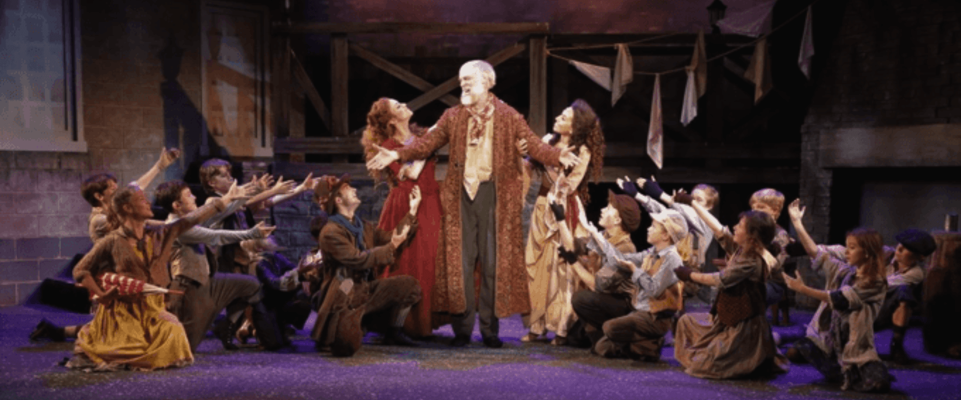 A theatrical performance with a central character in elaborate costume surrounded by a group of actors reaching out towards him.