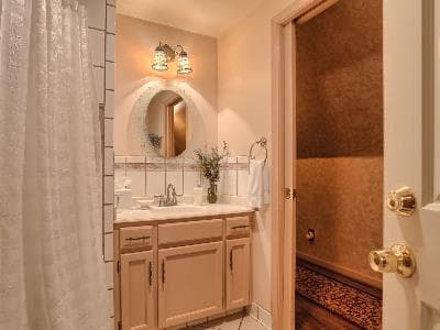 A cozy bathroom featuring a sink, mirror, and shower with warm lighting.