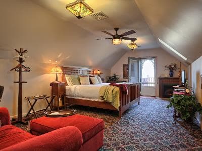 Spacious attic bedroom with a king-size bed, cozy seating area, and decorative lighting.