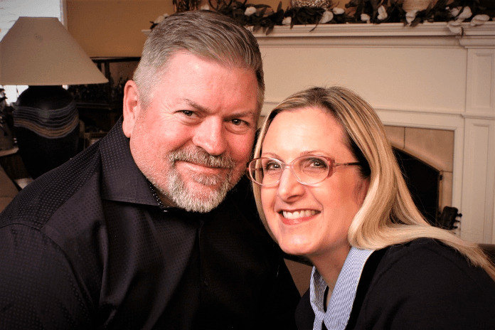 A man and a woman smile closely together in a cozy setting.