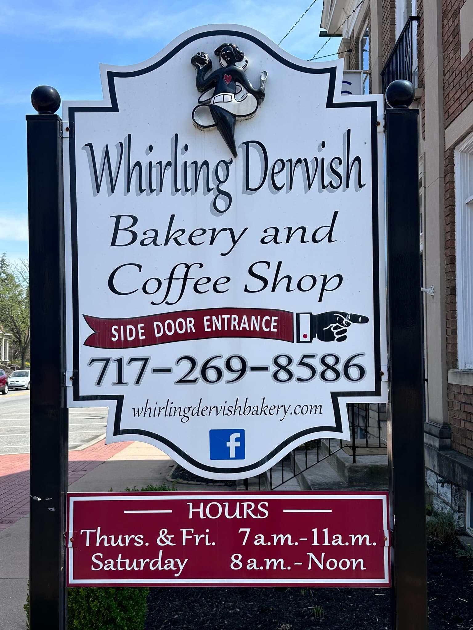 Sign for Whirling Dervish Bakery and Coffee Shop displaying contact information and hours of operation.