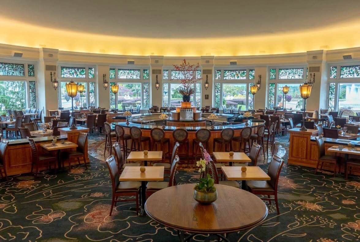A spacious restaurant interior featuring circular seating and large windows.