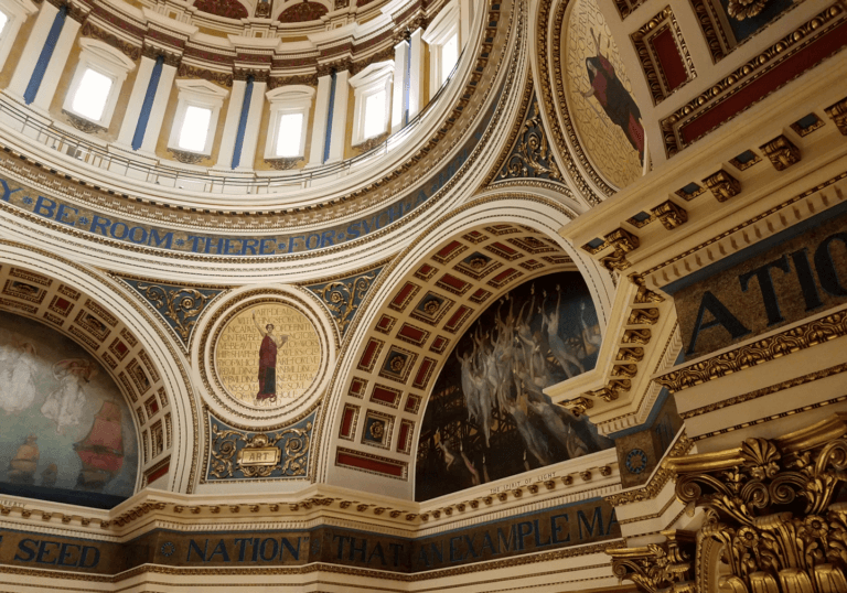Ornate architectural details and murals inside a historic dome.