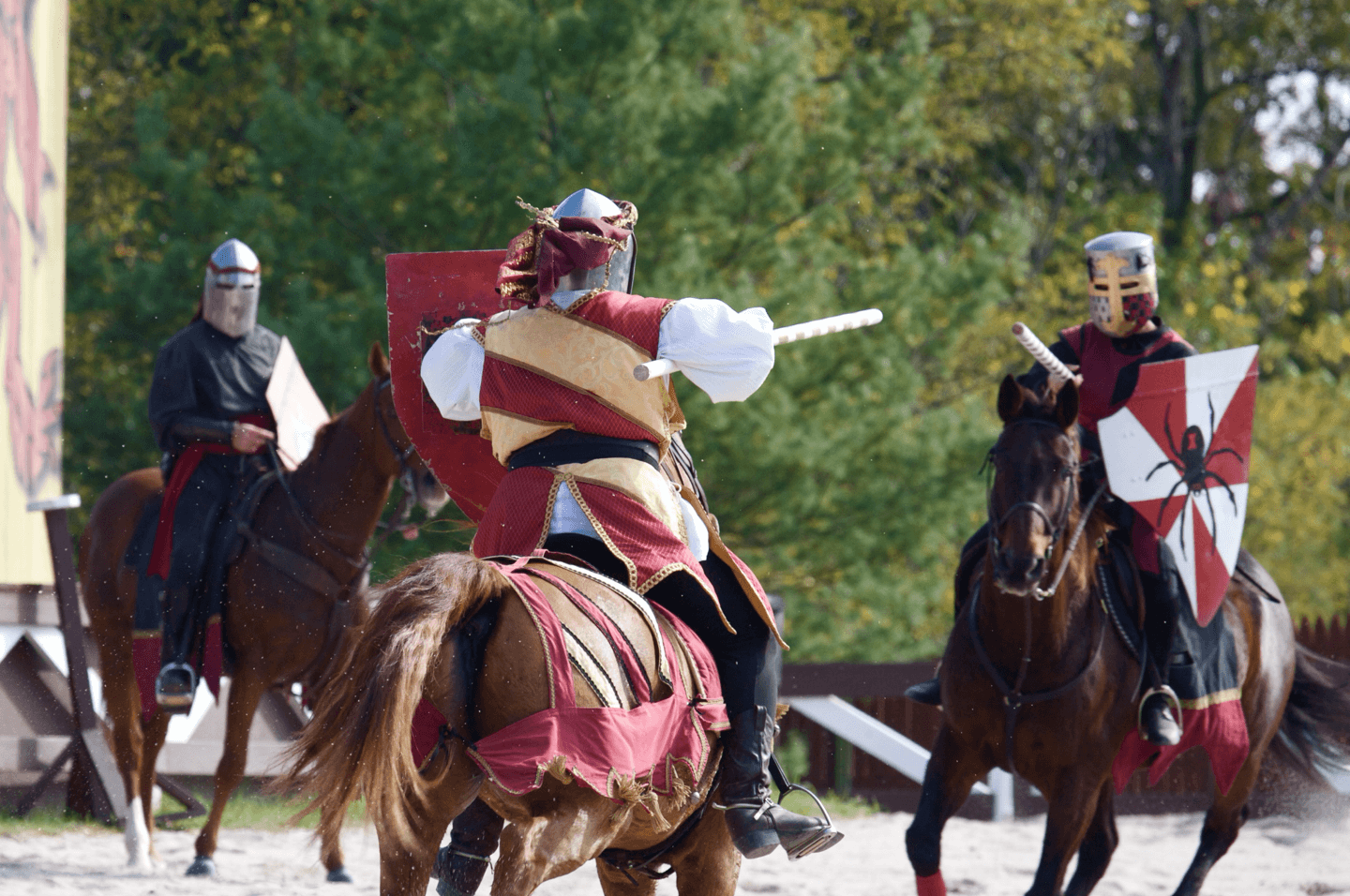 Two knights in armor engage in a mock battle on horseback in a wooded area.