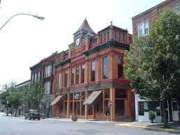 Historic building with a bright wooden facade and decorative clock tower on a city street.