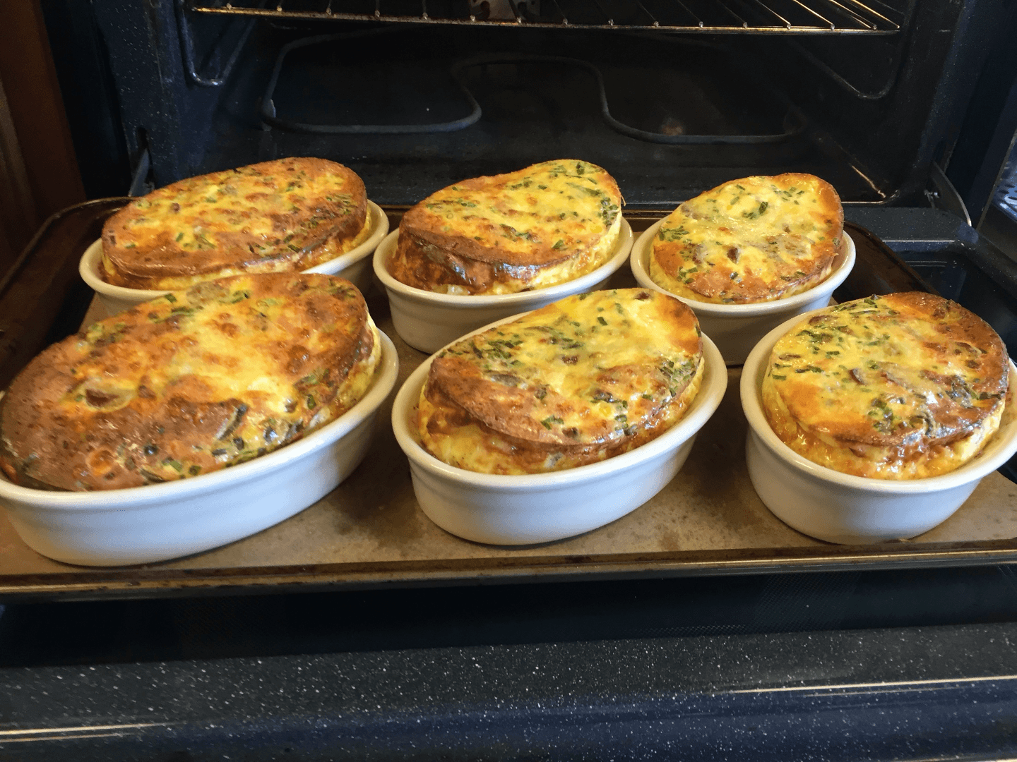 A tray of freshly baked vegetable frittatas in individual white dishes.