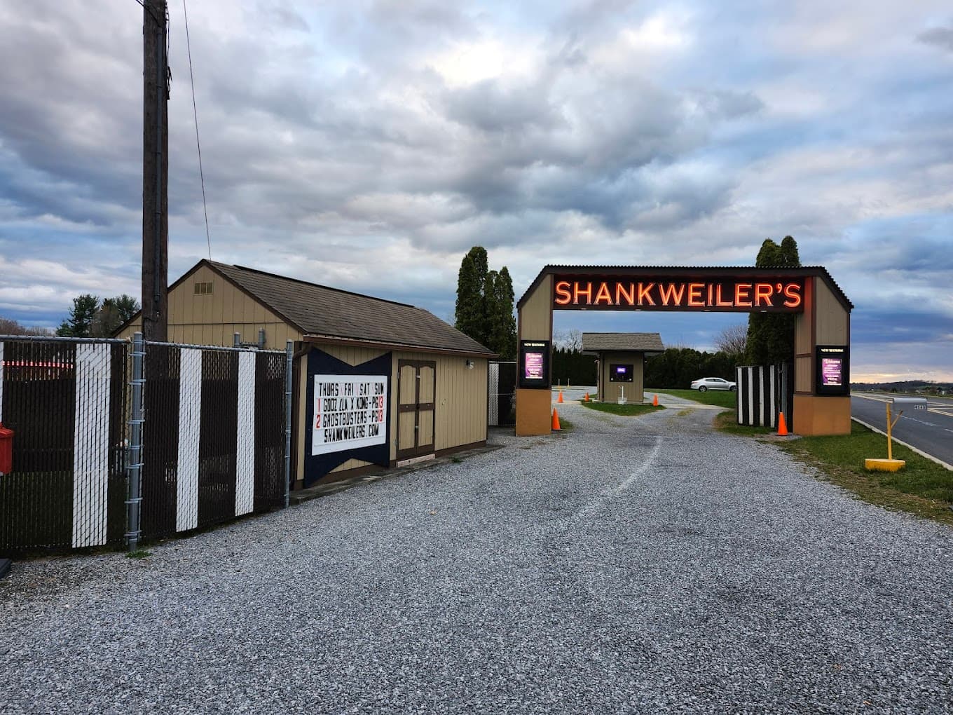 Entrance to Shankweilers, a drive-in theater, with a gravel pathway and cloudy sky.