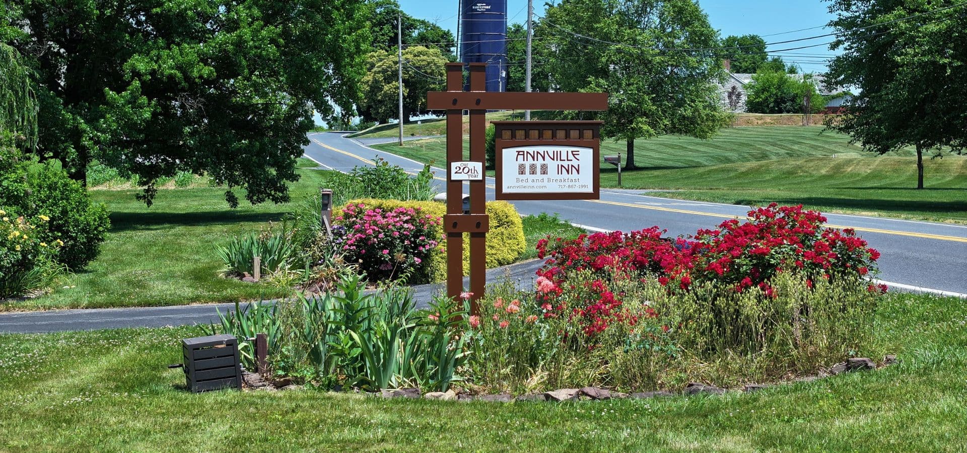 Sign for Annville Inn surrounded by colorful flowers and greenery along a road.