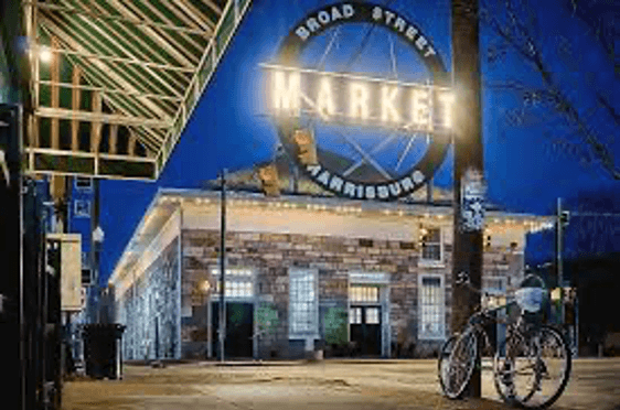 A nighttime view of the Broad Street Market building in Harrisburg, illuminated with a large sign.
