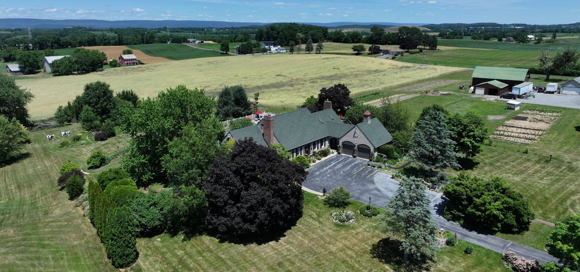 Aerial view of a spacious rural property featuring a house surrounded by trees and farmland.