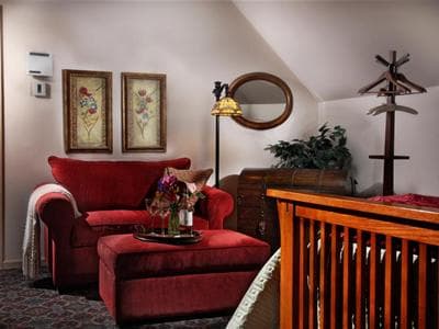 Cozy corner of a room with a red armchair, floral decorations, and wooden furnishings.