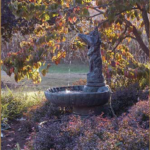 Fountain in the Welcome Garden, backlit in Autumn with the sun streaming through golden leaves.
