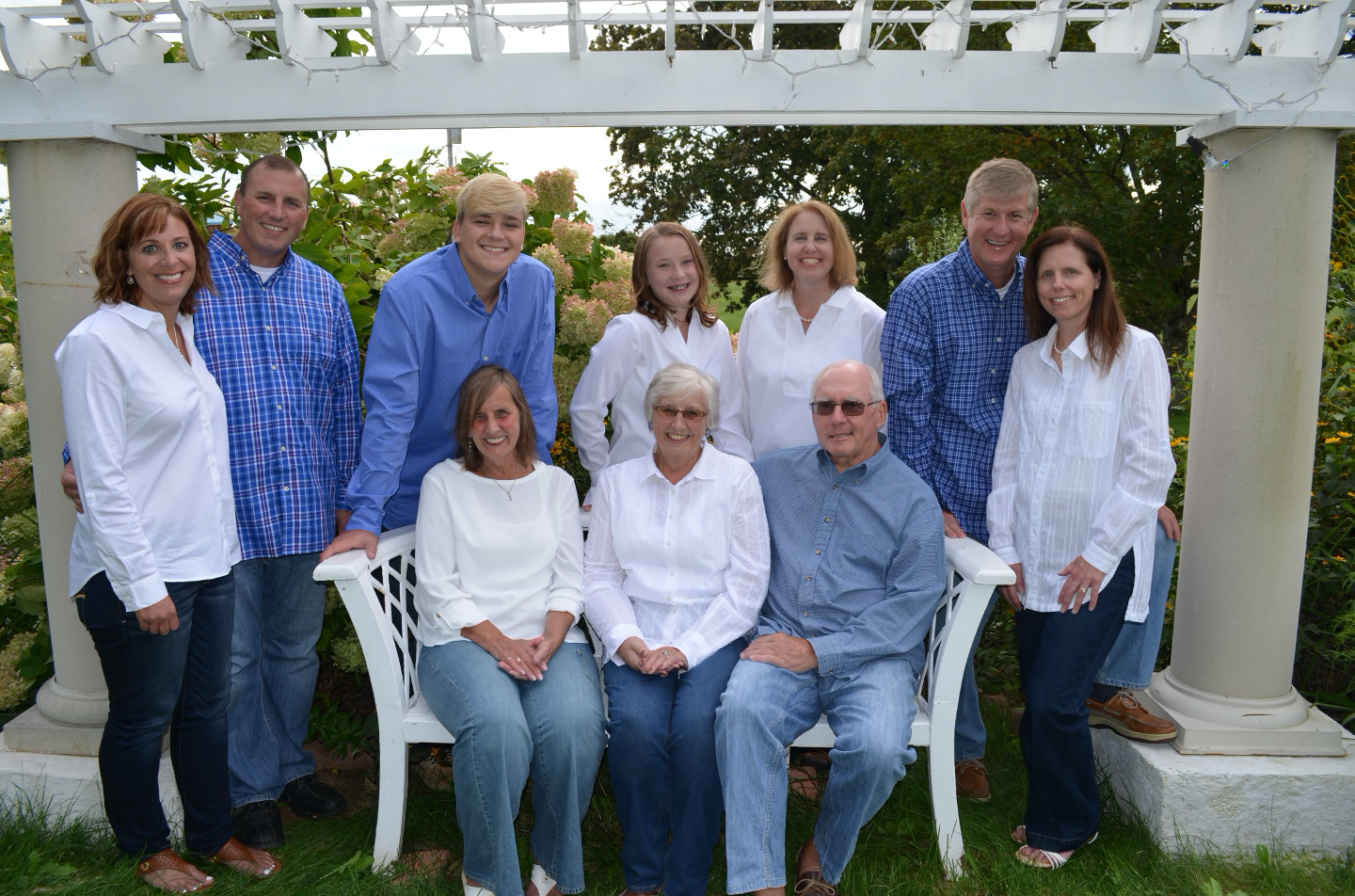 Family Group of of ten outdoors posing for portrait, all wearing blue and white.
