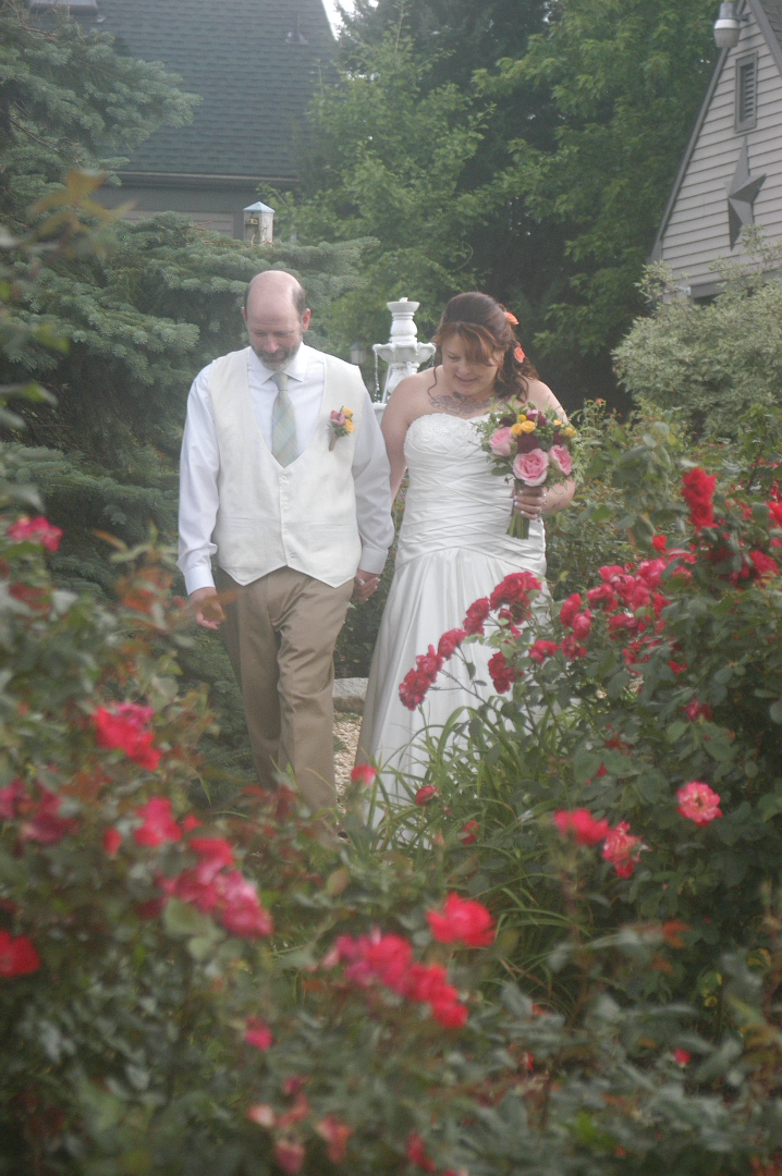 Bride and Groom walking through rose garden at Annville Inn B&B
