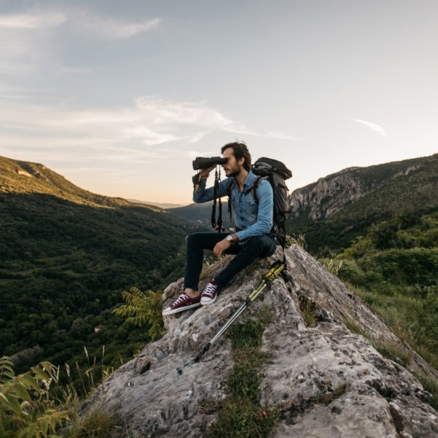 man on mountaintop with binoculars birdwatching