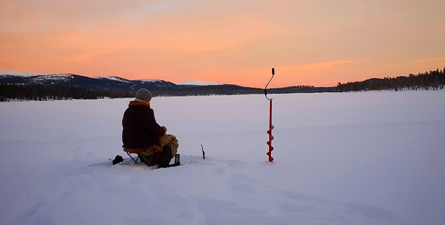 Ice fishing at sunset on frozen lake