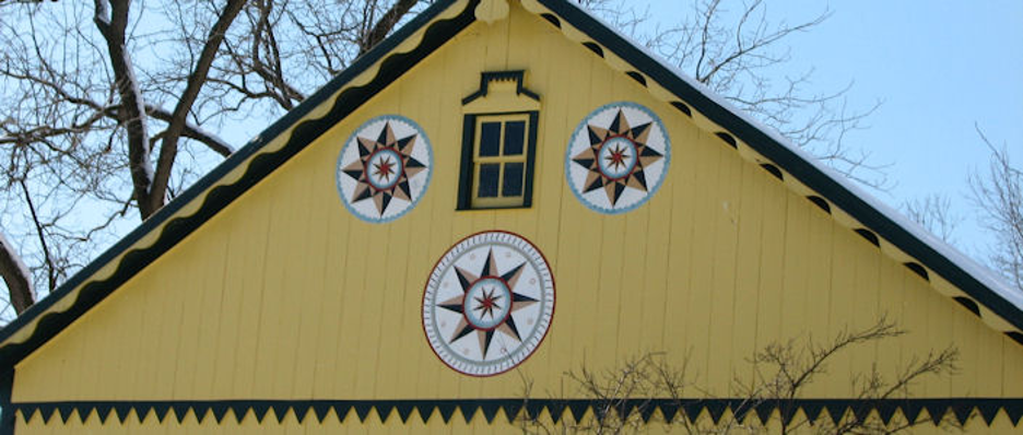yellow barn with three Amish "Hex Symbols"