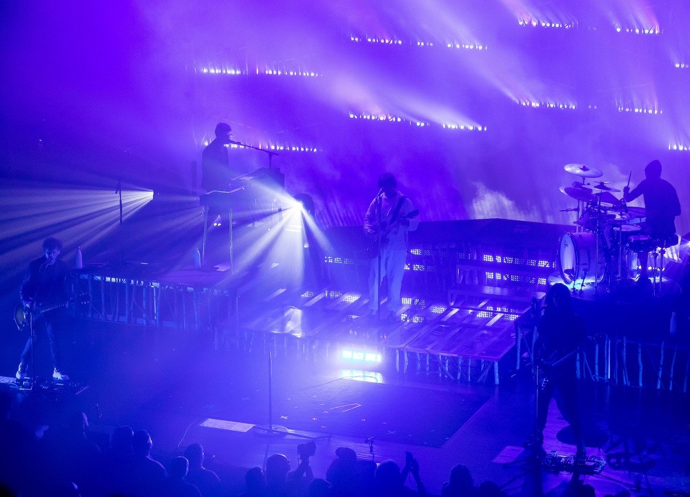 The 90's pop group,"Third Eye Blind" in concert, on stage. Stage / set is bathed in purple light, with the singers positioned across the stage.