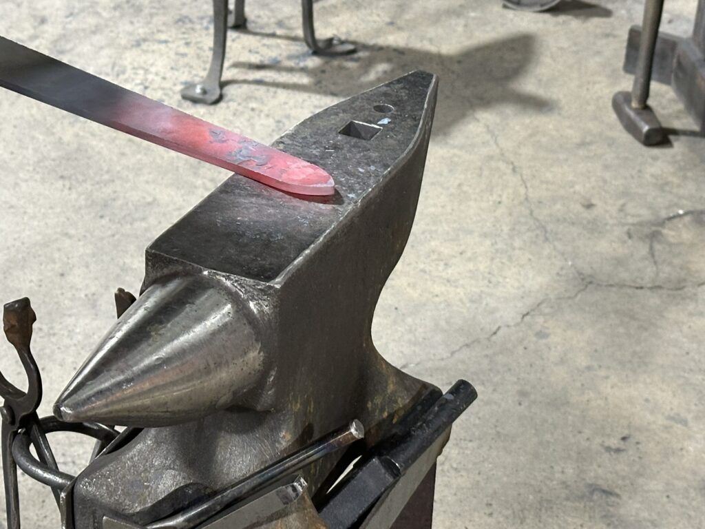 Photo of a anvil with a sword being forged at the Drunken Smith