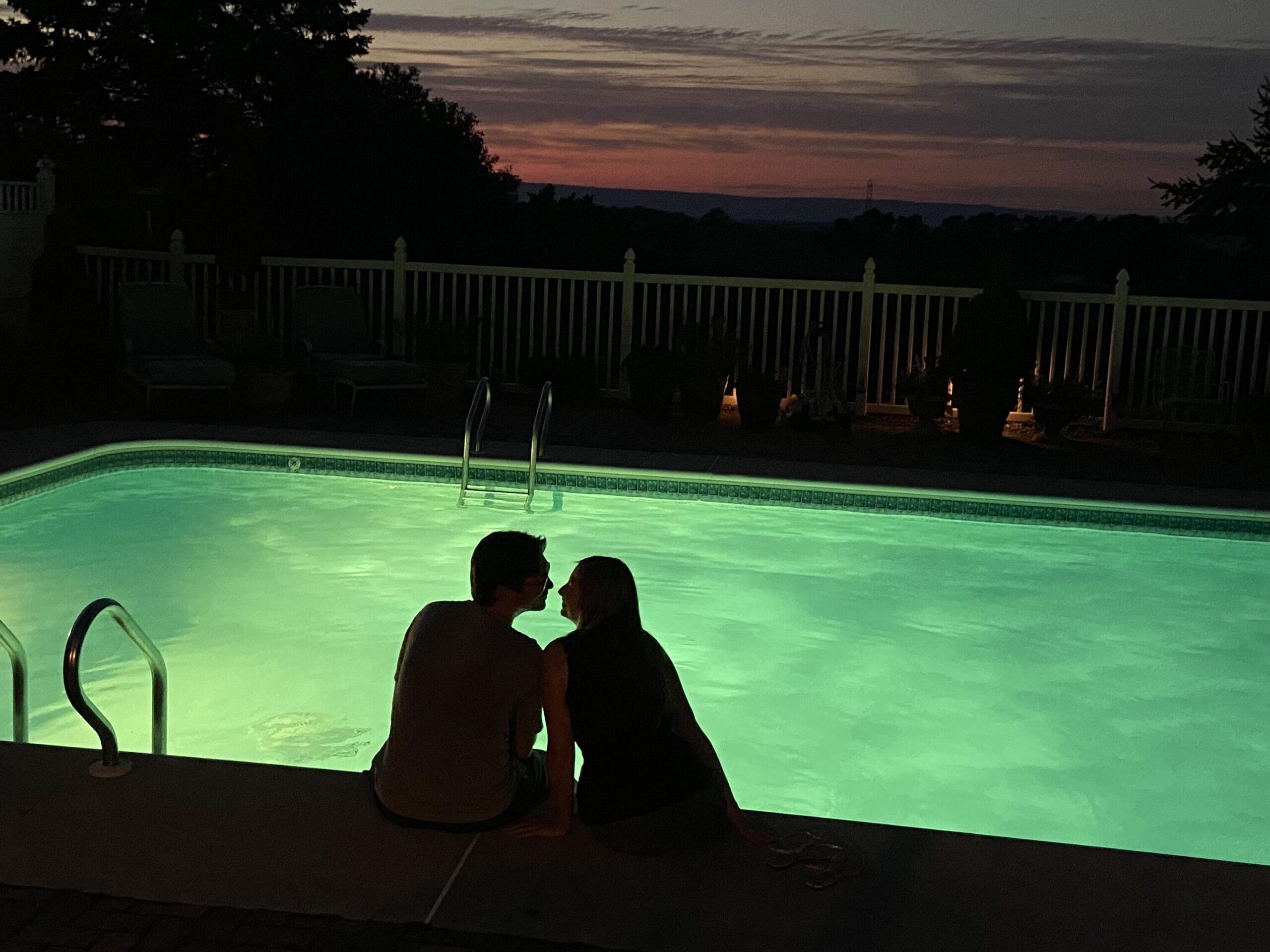 Silhouette of a couple sitting next to a pool while the sun sets. Valentines in Hershey